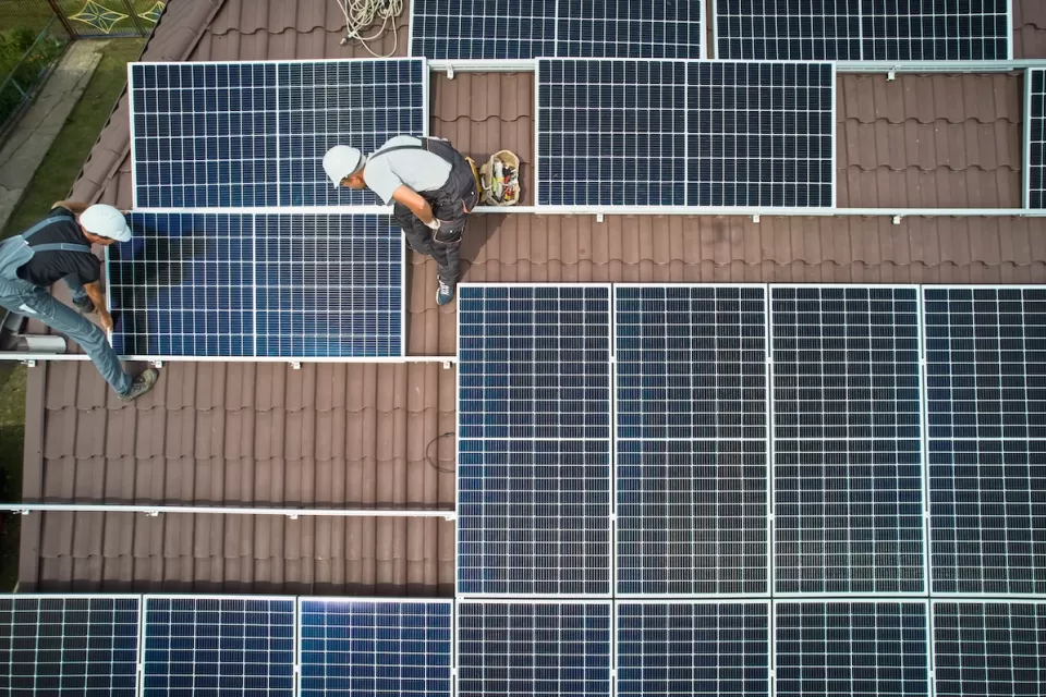 Bird's eye view of workers installing solar panels on rooftop.
